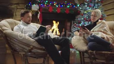 成年男子在智能手机上上网，而妇女则在圣诞夜看书